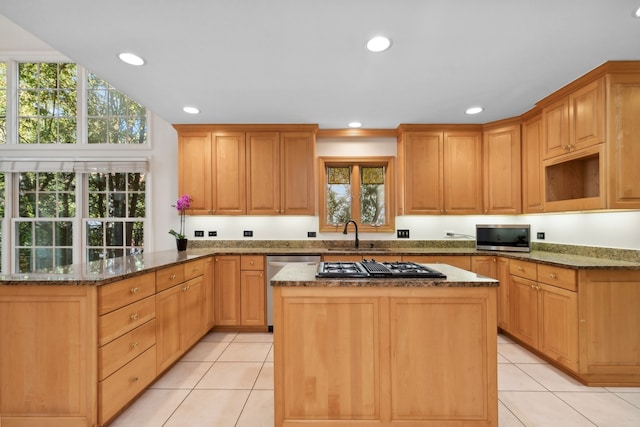 kitchen featuring dark stone counters, sink, kitchen peninsula, appliances with stainless steel finishes, and light tile patterned floors