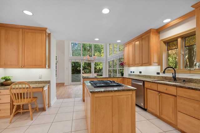 kitchen with a wealth of natural light, appliances with stainless steel finishes, dark stone counters, and a kitchen island