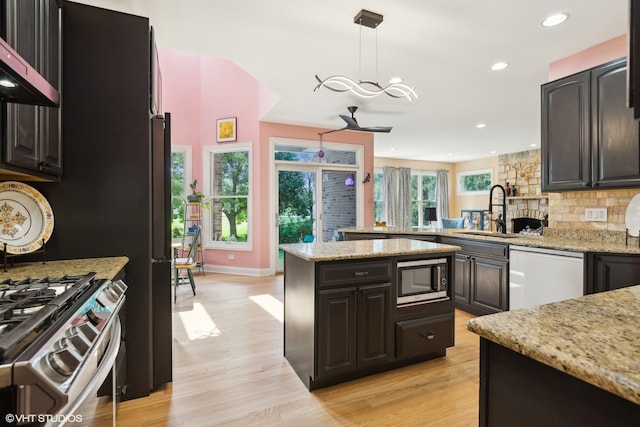 kitchen with stainless steel appliances, light stone countertops, hanging light fixtures, and sink