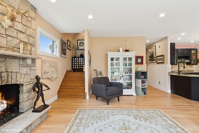 sitting room with light wood-type flooring and a stone fireplace