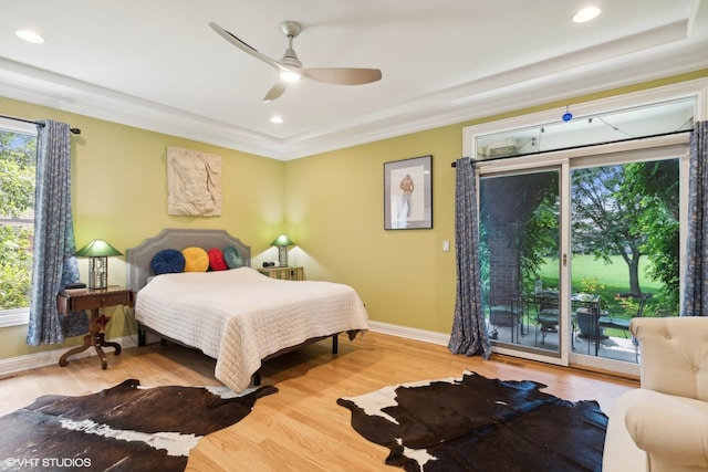 bedroom featuring ceiling fan, wood-type flooring, crown molding, access to exterior, and a tray ceiling