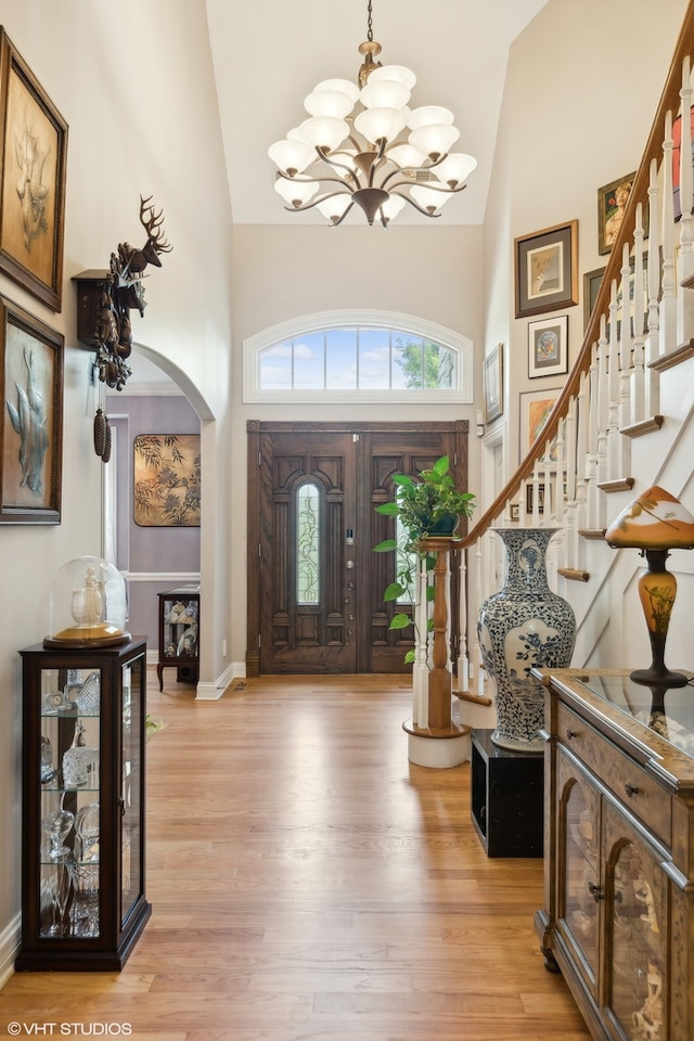 foyer with light wood-type flooring and high vaulted ceiling