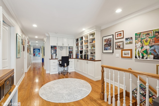 home office with ornamental molding, light wood-type flooring, and built in desk