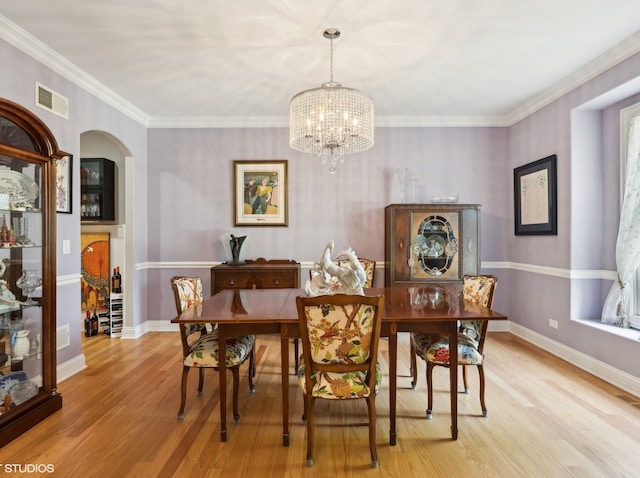 dining area with crown molding, a chandelier, and light hardwood / wood-style floors