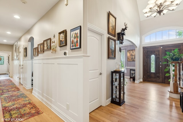 entrance foyer with light wood-type flooring, a notable chandelier, and lofted ceiling