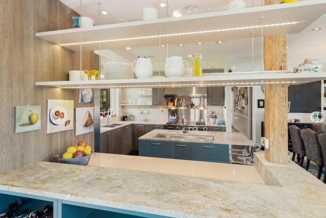 kitchen featuring light stone countertops, a kitchen island, sink, and decorative light fixtures