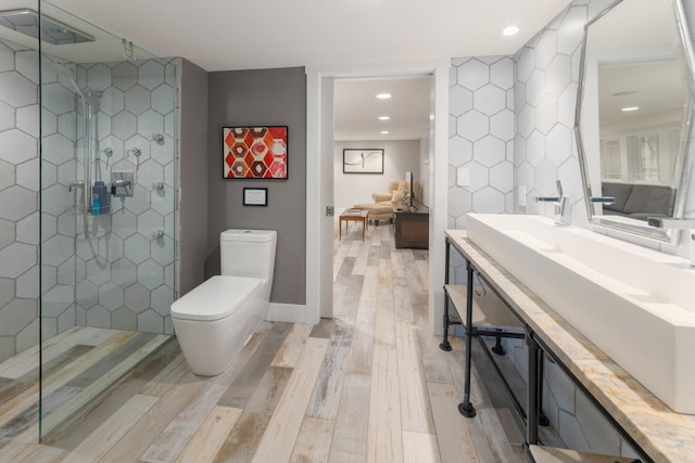 bathroom featuring hardwood / wood-style flooring, vanity, toilet, and a tile shower