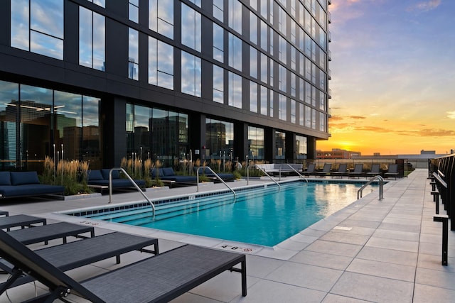 pool at dusk with a patio area