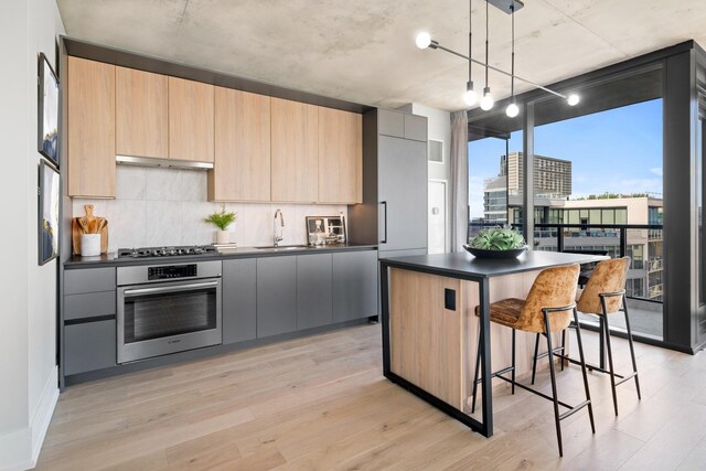 kitchen featuring light wood-type flooring, pendant lighting, a center island, and stainless steel appliances