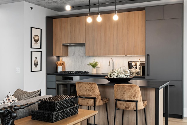 kitchen with backsplash, stainless steel appliances, decorative light fixtures, light hardwood / wood-style floors, and a breakfast bar area