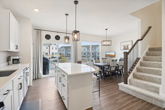 kitchen with a center island, hanging light fixtures, white cabinetry, a breakfast bar area, and dark hardwood / wood-style floors