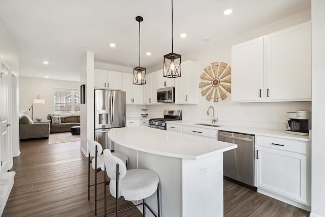 kitchen with white cabinetry, stainless steel appliances, dark wood-type flooring, sink, and a center island