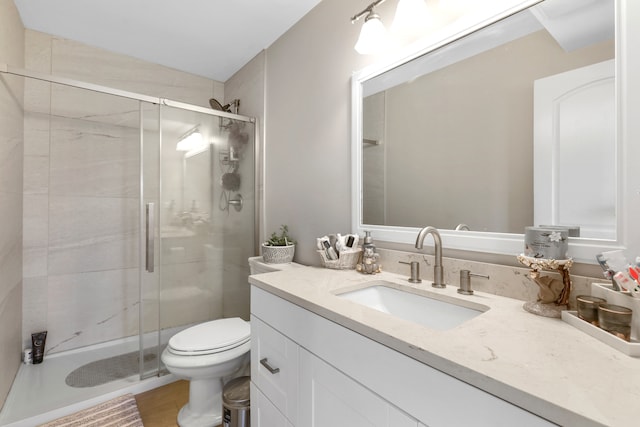 bathroom featuring toilet, vanity, and a shower with shower door