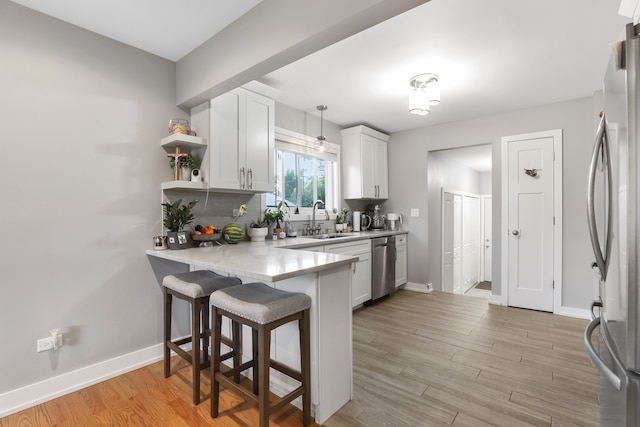 kitchen with white cabinets, appliances with stainless steel finishes, hanging light fixtures, and sink