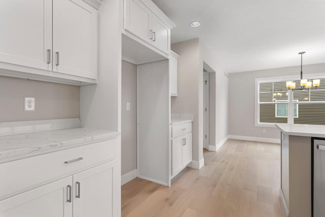 kitchen with light hardwood / wood-style flooring, decorative light fixtures, light stone counters, white cabinetry, and a chandelier