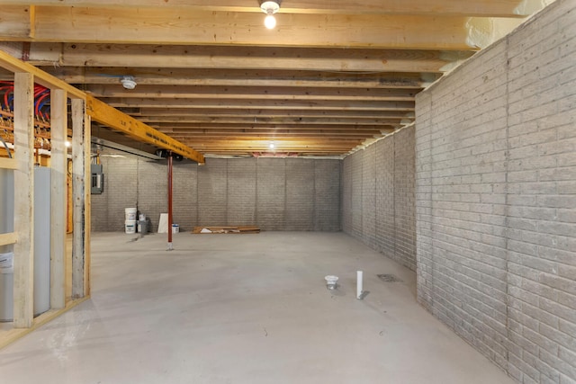 basement featuring electric panel and brick wall