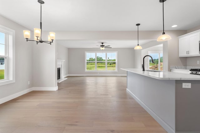 kitchen featuring pendant lighting, ceiling fan with notable chandelier, light hardwood / wood-style floors, and sink