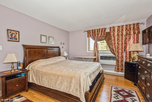 bedroom featuring cooling unit, a baseboard heating unit, and light wood-type flooring