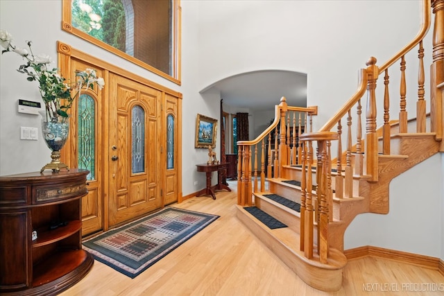 entrance foyer featuring a towering ceiling and light hardwood / wood-style floors