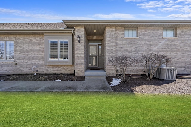 view of exterior entry with central AC unit and a lawn