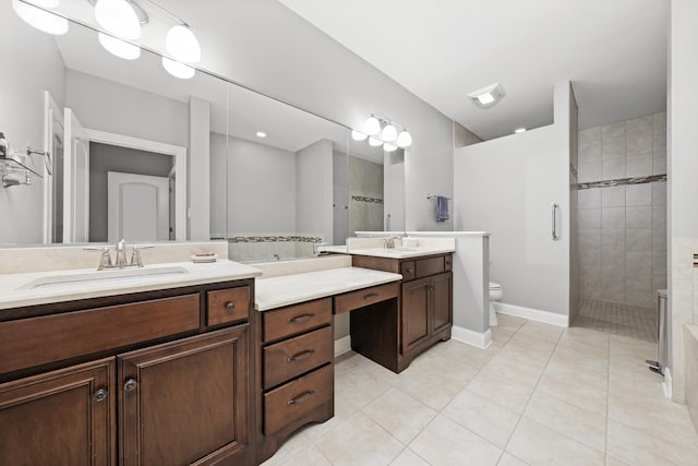 bathroom featuring vanity, a tile shower, tile patterned floors, and toilet