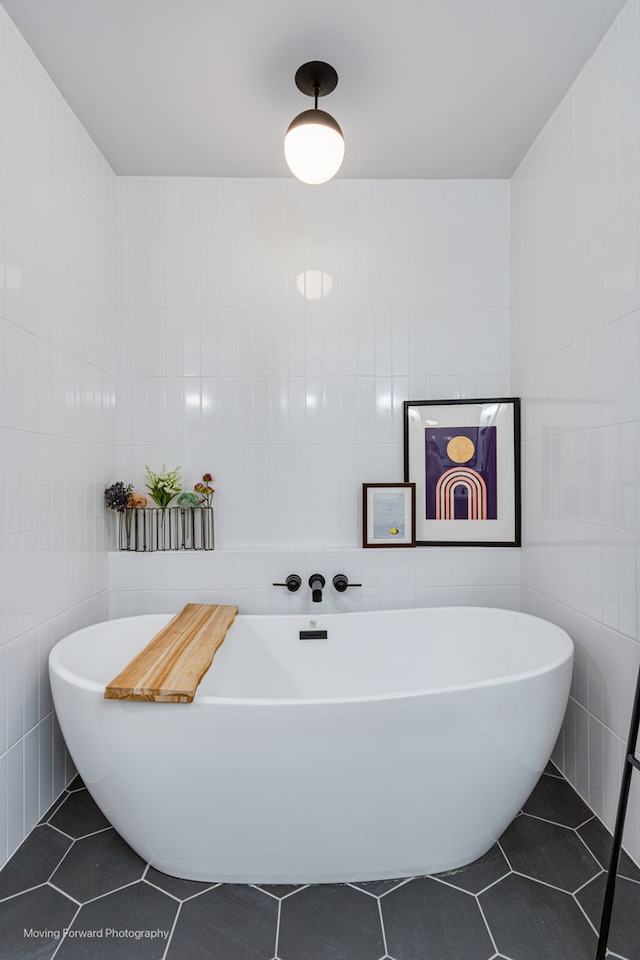 bathroom featuring a tub, tile patterned flooring, and tile walls