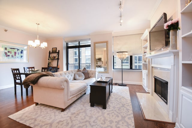 living room featuring a high end fireplace, a chandelier, crown molding, and dark hardwood / wood-style floors