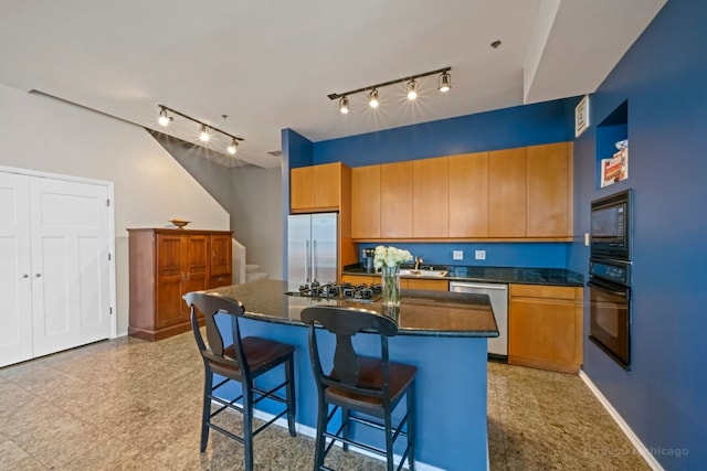 kitchen featuring sink, a kitchen island, rail lighting, black appliances, and a breakfast bar area