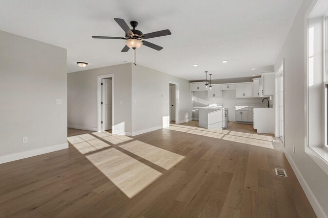 unfurnished living room with sink, light hardwood / wood-style floors, and ceiling fan with notable chandelier