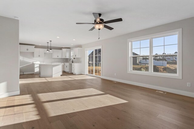 kitchen with light wood-type flooring, pendant lighting, white cabinets, a chandelier, and a kitchen island