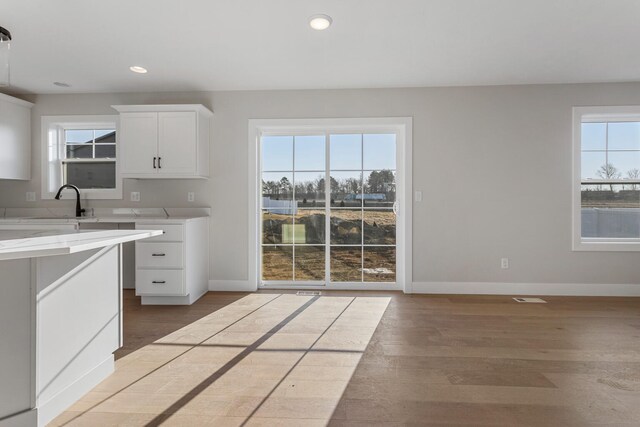 kitchen featuring light stone countertops, sink, white cabinets, and light hardwood / wood-style flooring