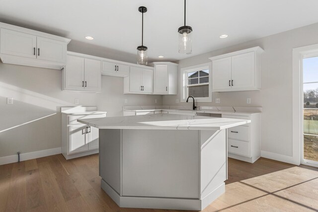 kitchen featuring white cabinets, light hardwood / wood-style floors, a kitchen island, and sink