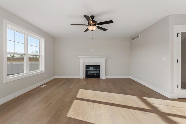 unfurnished living room featuring ceiling fan, a fireplace, and light wood-type flooring