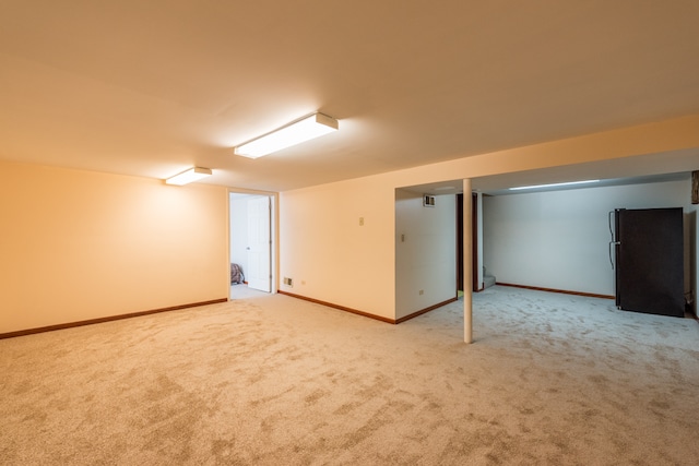 basement with light colored carpet and black fridge