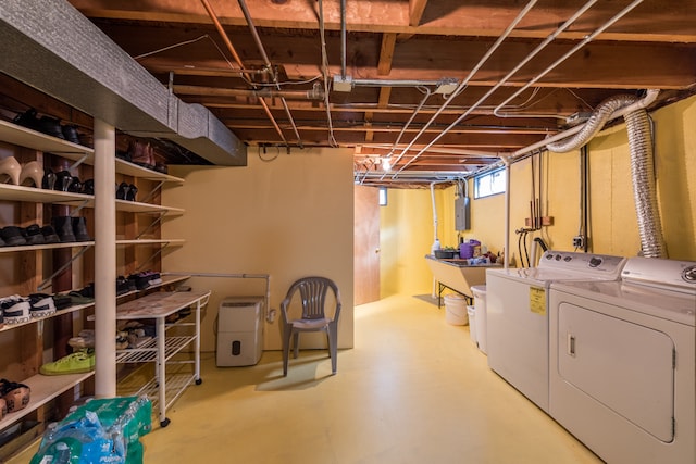 basement featuring electric panel and washing machine and clothes dryer