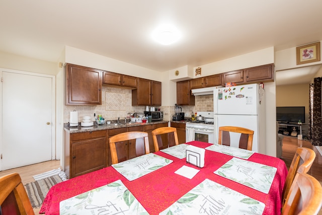 kitchen with sink, decorative backsplash, light wood-type flooring, and white appliances