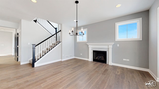 unfurnished living room with hardwood / wood-style flooring, a chandelier, and plenty of natural light