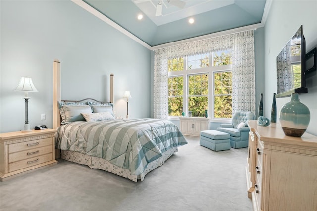 bedroom featuring a high ceiling, a tray ceiling, ornamental molding, light colored carpet, and ceiling fan