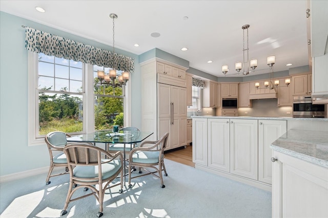 kitchen with light carpet, stainless steel oven, decorative light fixtures, and built in microwave