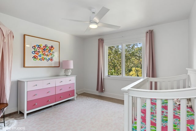 bedroom with ceiling fan, light hardwood / wood-style floors, and a nursery area