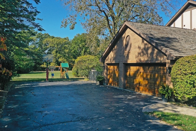 view of side of property featuring a yard, a playground, an outbuilding, and a garage