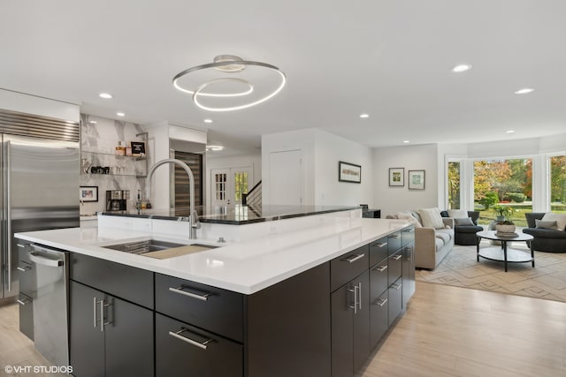 kitchen featuring light hardwood / wood-style floors, appliances with stainless steel finishes, sink, and a center island with sink