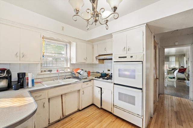 kitchen with white double oven, light hardwood / wood-style flooring, sink, white cabinetry, and tasteful backsplash