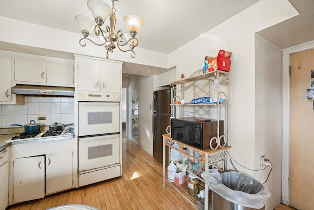 kitchen with decorative backsplash, white cabinets, light hardwood / wood-style flooring, double oven, and decorative light fixtures