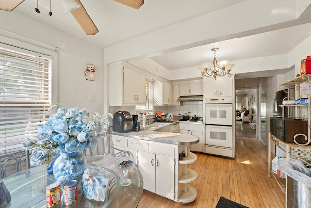 kitchen with light hardwood / wood-style flooring, white cabinetry, white double oven, and backsplash