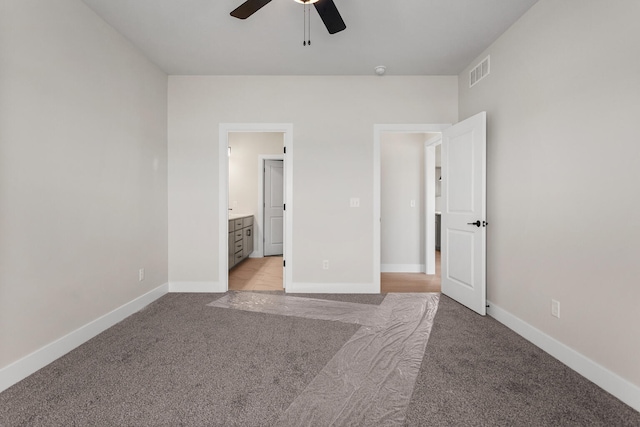 unfurnished bedroom featuring visible vents, light colored carpet, ensuite bath, and baseboards