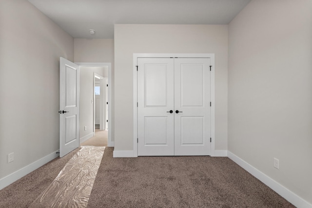 unfurnished bedroom with a closet, baseboards, and carpet floors