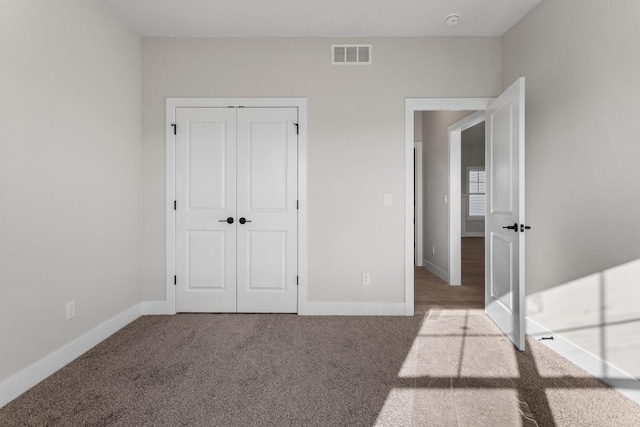 unfurnished bedroom with visible vents, carpet floors, and baseboards