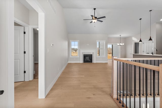 corridor with visible vents, light wood-style flooring, baseboards, and vaulted ceiling