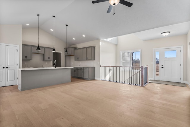 unfurnished living room featuring baseboards, high vaulted ceiling, light wood-style flooring, and a ceiling fan